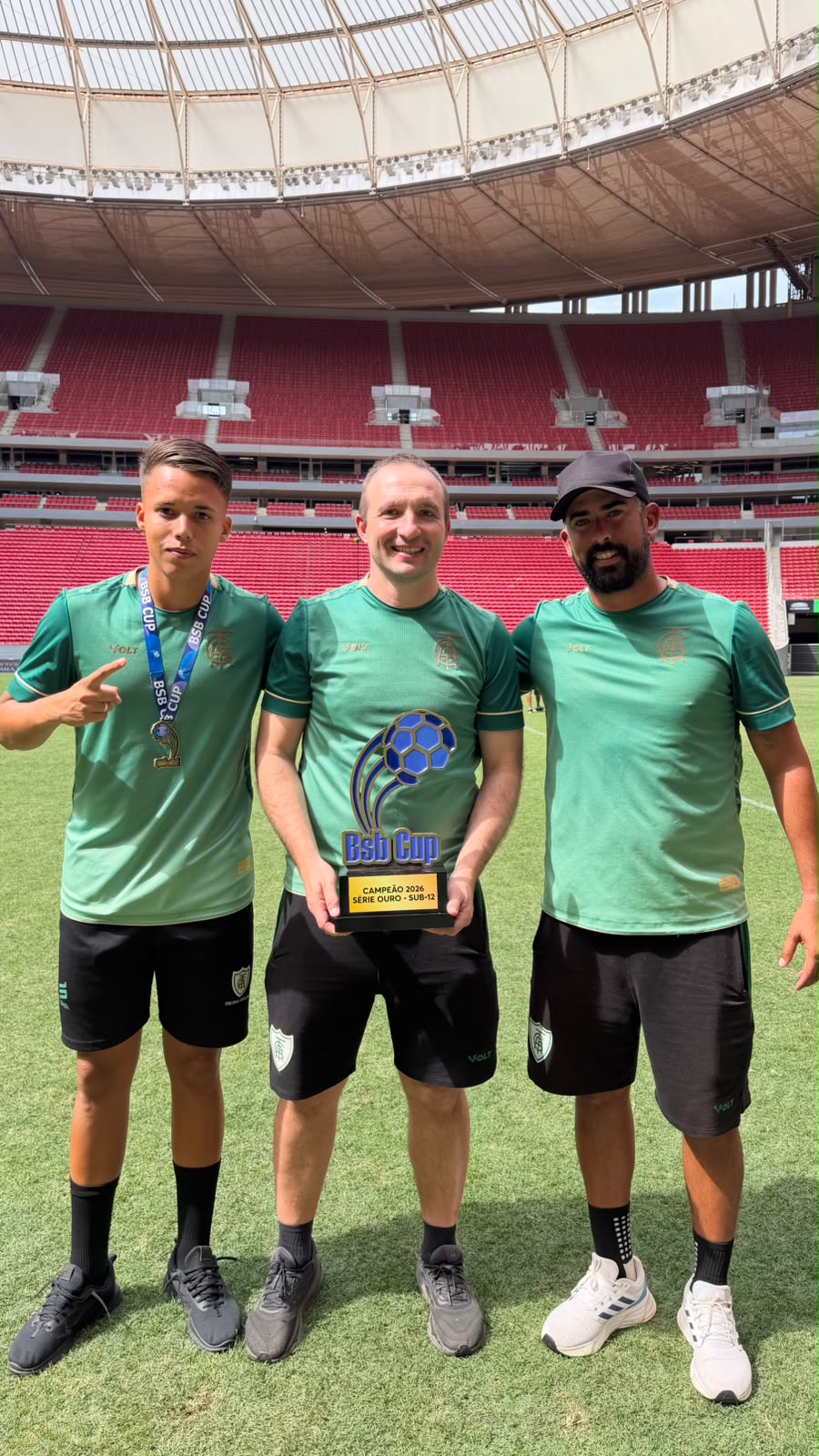 Comissão técnica da América Mineiro comemorando título com o troféu